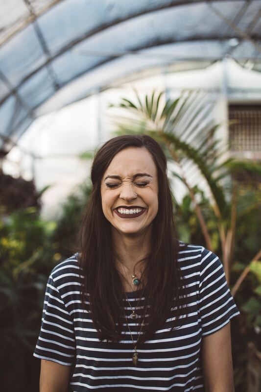 Brunette woman in striped shirt laughing in a greenhouse 