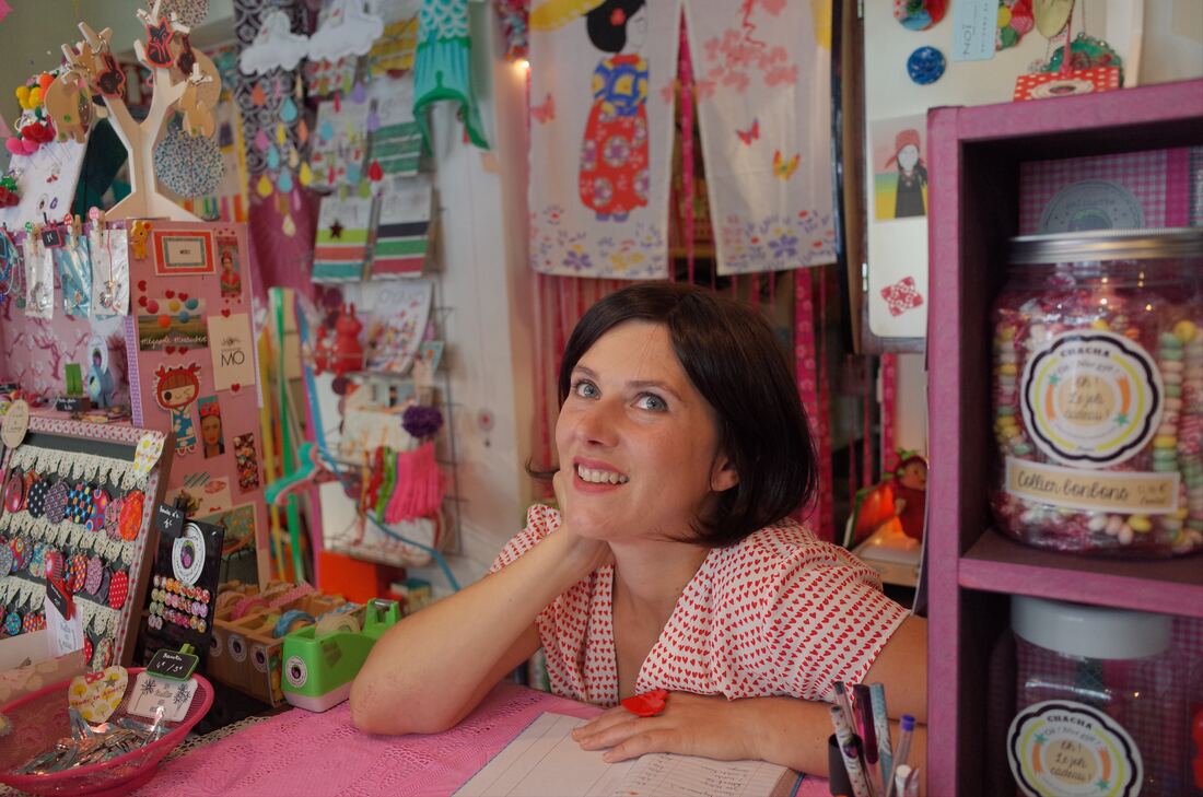Woman sitting in her pretty pink craft market stall